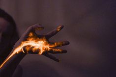 a woman holding out her hand with fire painted on it in front of her face