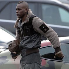 a man walking down the street with his handbag in his other hand and wearing a jacket