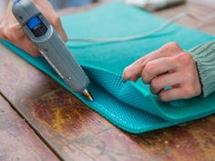 a person using a knife to cut something on a piece of blue material with a green mat