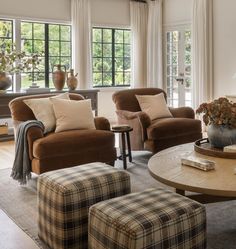 a living room with couches, chairs and a coffee table in front of two windows