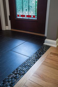 a wooden door with a glass window in the background and tile on the floor next to it