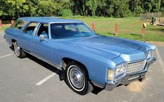 an old blue station wagon parked in a parking lot