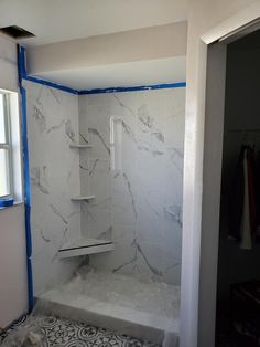 a bathroom that is being remodeled with blue tape on the shower walls and flooring