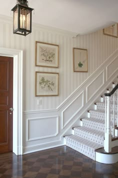 a staircase with pictures on the wall and a lantern hanging from it's side