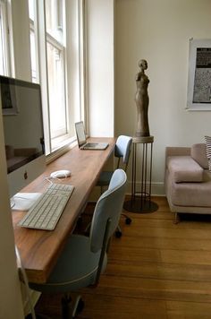 a living room filled with furniture and a computer on top of a wooden desk in front of a window