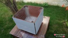 an old refrigerator sitting on top of a wooden pallet in the grass next to a tree