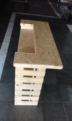 a table made out of wooden pallets sitting on top of a black tile floor