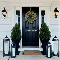 front door decorated with lanterns and wreaths for the holiday season, including two large potted trees