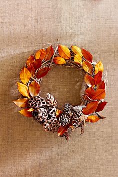 a wreath made out of leaves and pine cones on a burlocked surface