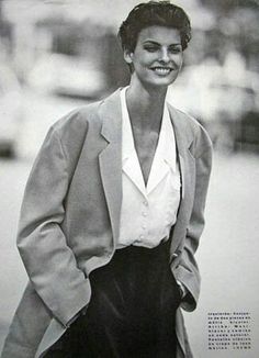 a black and white photo of a woman wearing a jacket, shirt and skirt with her hands in her pockets