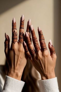 the woman is holding her hands up with henna tattoos on their palms and fingers