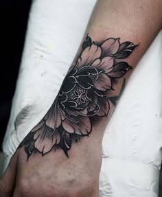 a black and white flower tattoo on the left hand