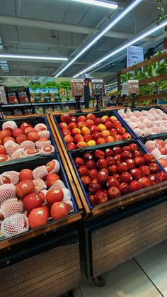 apples and other fruits are on display in the produce section of a grocery store,