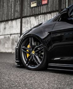 a black sports car parked in front of a building with its wheels on the ground