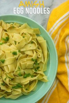 a blue bowl filled with pasta and parsley on top of a yellow towel next to an orange towel