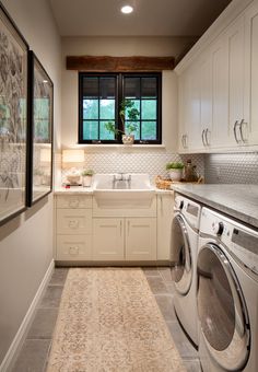 a washer and dryer in a small room with white cabinets on the walls