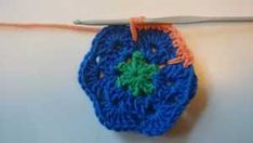 a crocheted blue flower with green leaves is hanging from a hook on a white wall