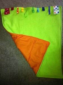 an orange and green cloth with colorful pins on it sitting on the floor next to a pair of scissors