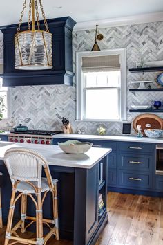 a kitchen with blue cabinets and white counter tops, an island in the middle has a bowl on it