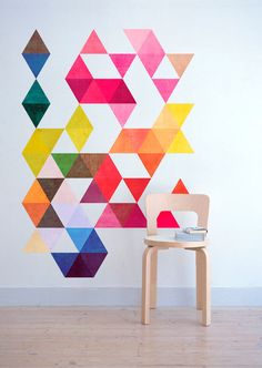 an image of a chair in front of a wall with colorful geometric shapes on it