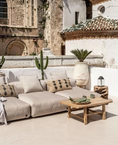 a couch sitting on top of a white floor next to a potted plant in front of a building