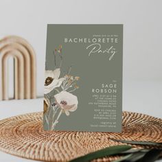 a card with flowers on it sitting on top of a wicker place mat next to a plant