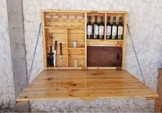 a wooden table topped with bottles of wine and a metal chain hanging from the wall