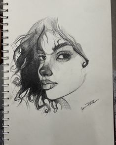 a pencil drawing of a woman's face with curly hair and eyes, on paper