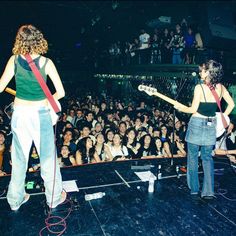 two women on stage with guitars in front of an audience