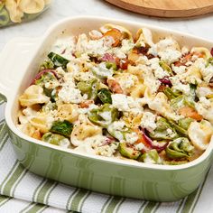 a green casserole dish filled with pasta and vegetables