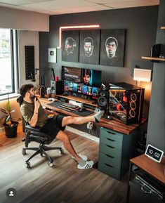 a man sitting at a desk in front of a computer monitor and keyboard with headphones on