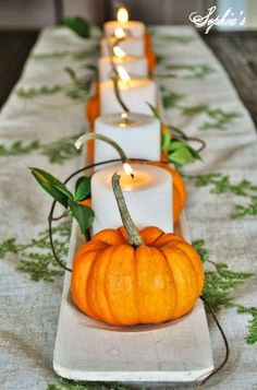 candles are lined up on a table with pumpkins