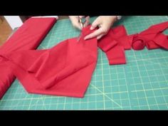 someone is cutting out red fabric on a green table with scissors and paper cutters