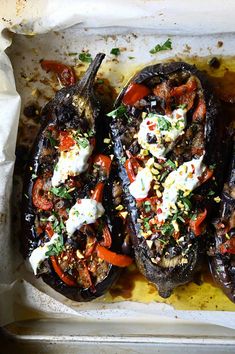 three stuffed peppers with various toppings in a baking dish