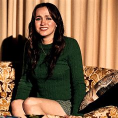 a woman is sitting on a couch smiling