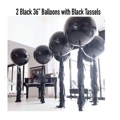 black balloons with tassels are in the middle of a room