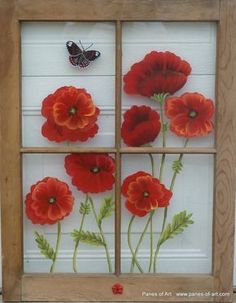 an old window with red flowers and a butterfly on the glass in front of it