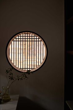 a round window with bars on it in the wall next to a potted plant