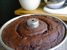 a chocolate cake in a pan on a cooling rack next to a coffee pot and mixer