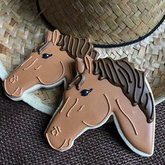 two cookies shaped like horses sitting on top of a table next to a straw hat