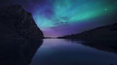 the sky is filled with colorful lights as it shines brightly over a body of water