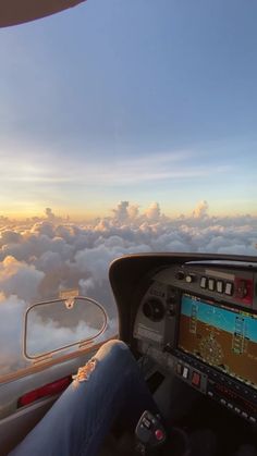 a person sitting in the cockpit of an airplane looking out at the clouds and sky