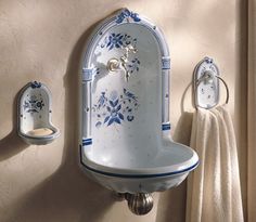 a white and blue sink mounted to the side of a wall next to a towel rack