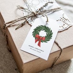 a gift wrapped in brown paper with a red ribbon and a green wreath on it