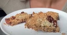 two pieces of food on a white plate with a woman's face in the background