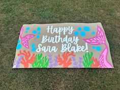 a birthday cake is on the grass and it says happy birthday sara bake