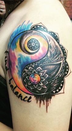 a colorful tattoo on the back of a woman's shoulder with an yin symbol