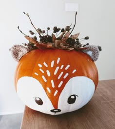 a pumpkin decorated like a fox with leaves on it's head is sitting on a table