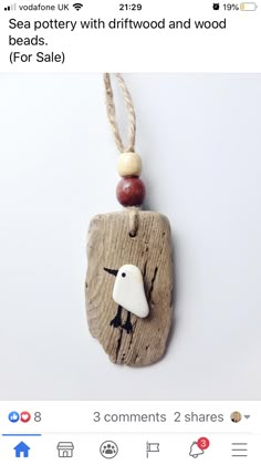 a piece of wood with a white bird on it's face and some beads attached to it