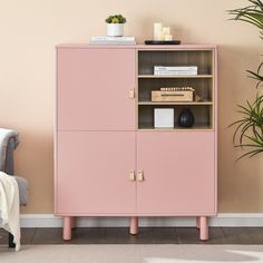 a pink cabinet next to a chair and potted plant